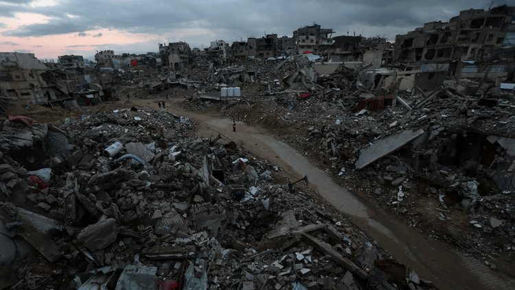 Palestinos caminham entre os escombros de edifícios destruídos em Khan Younis, no sul de Gaza, em 24 de fevereiro de 2025• Ramadan Abed / Reuters